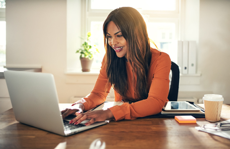 Smiling woman working on laptop at a desk